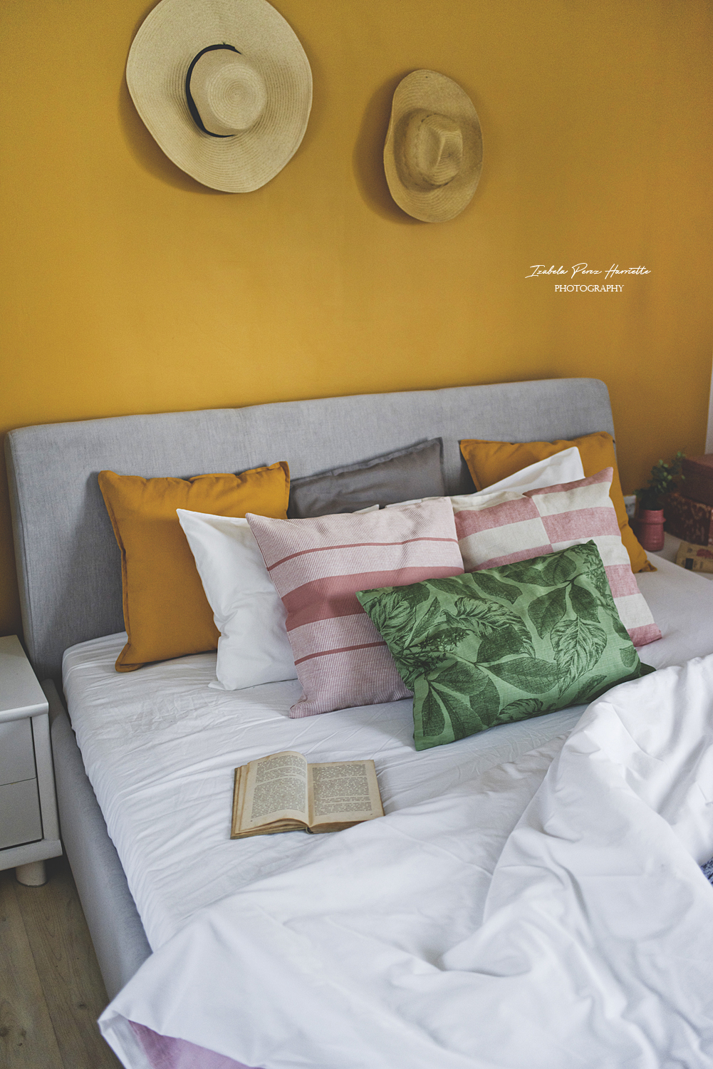sypialnia, miodowa ściana, tapicerowane łóżko, bukiet polnych kwiatów, lampki nocne, kapelusze na ścianie,kolorowe wnętrze